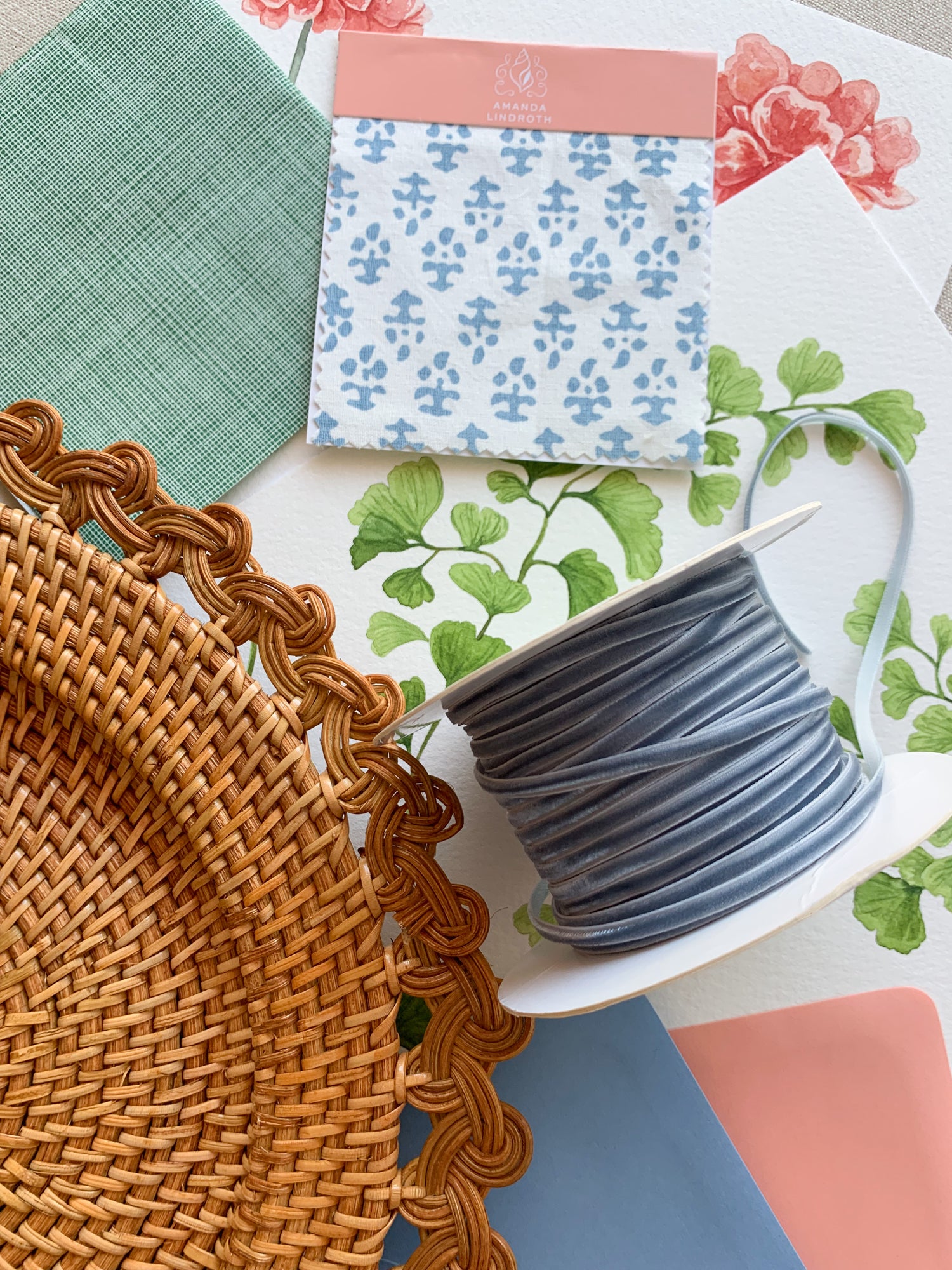 Light green cocktail napkin, white and blue batik swatch, light blue velvet thin ribbon, rattan charger and maidenhair fern watercolor artwork