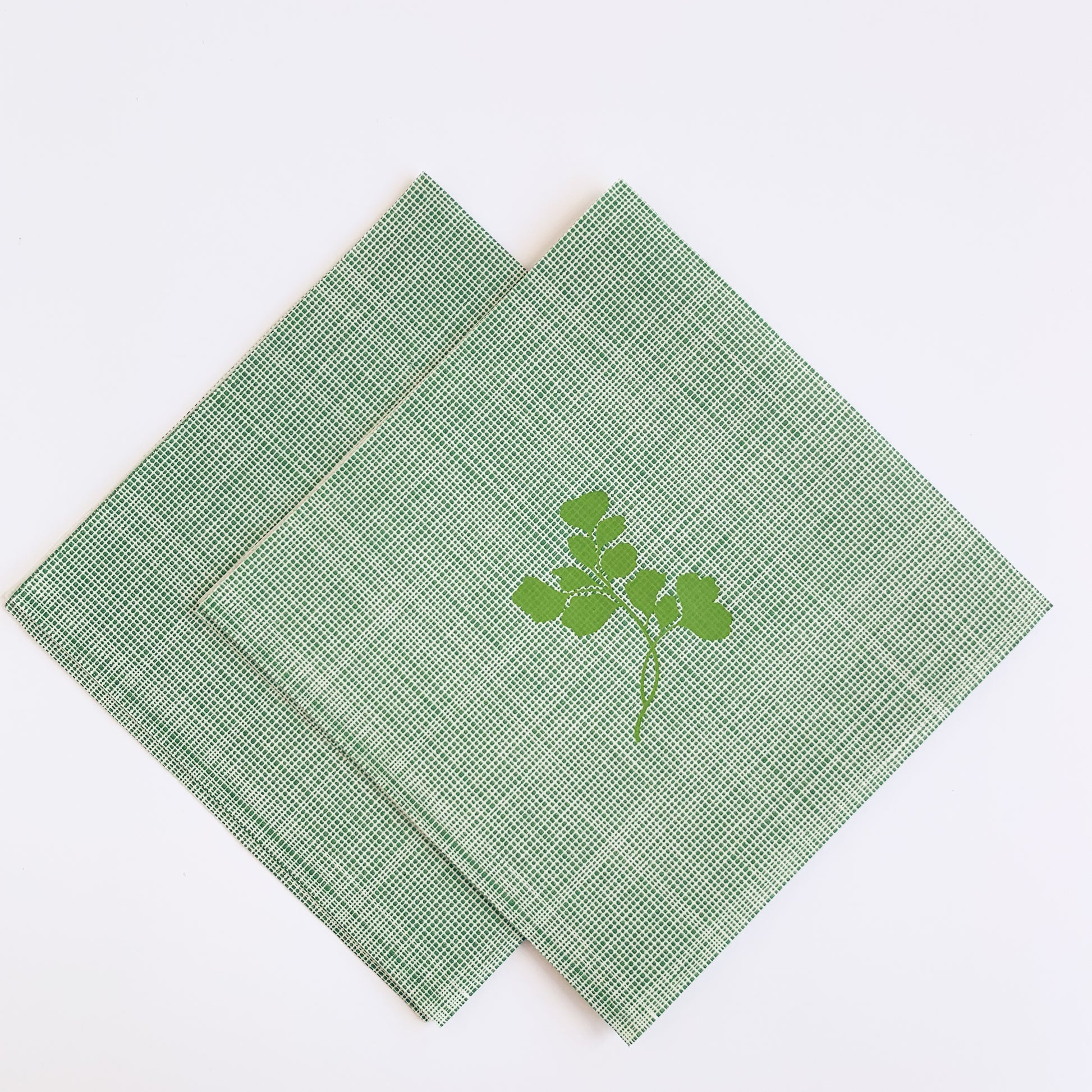 Light green, tweed patterned paper napkin with green maidenhair fern motif in center of napkin