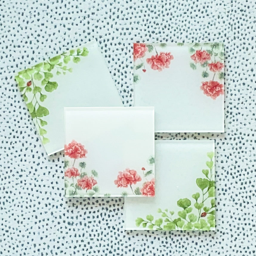 Four square acrylic place cards adorned with maidenhair fern greenery and red geranium watercolor artwork.