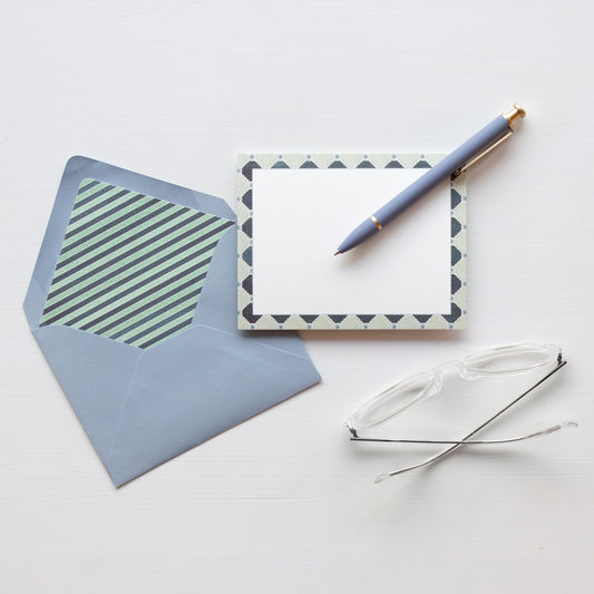 White notecard with navy, light blue and green tile patterned border. Light blue envelope lined with bold navy and green horizontal stripes.